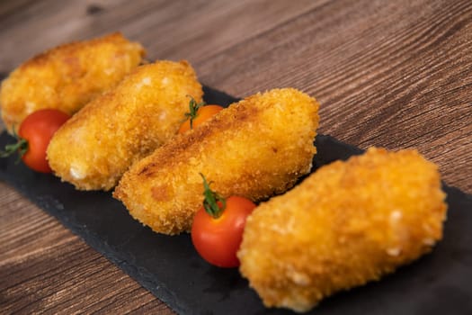Homemade traditional Spanish croquettes or croquetas on a black plate with fork, Tapas food, High quality photo