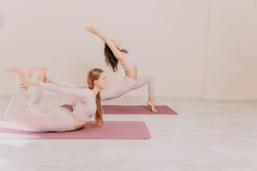 Young woman with long hair in white swimsuit and boho style braclets practicing outdoors on yoga mat by the sea on a sunset. Women's yoga fitness routine. Healthy lifestyle, harmony and meditation