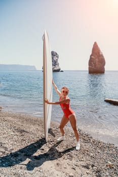 Close up shot of beautiful young caucasian woman with black hair and freckles looking at camera and smiling. Cute woman portrait in a pink bikini posing on a volcanic rock high above the sea