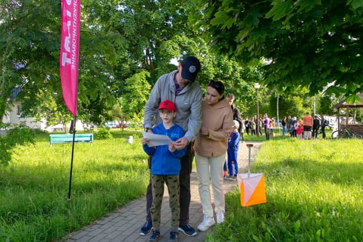 Grodno, Belarus - 15 June, 2022: Training of the Veras orienteering club . A young family of three people at the start of the route check the map and choose the direction to move.