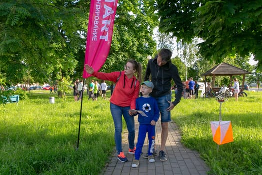 Grodno, Belarus - 15 June, 2022: Training of the Veras orienteering club . A young family of three people at the start of the route check the map and choose the direction to move.