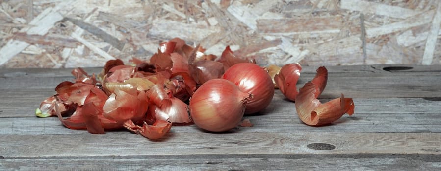 Food background with onion and husk on wooden natural background.The concept of onion health benefits for people.
