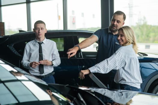 Happy caucasian couple choosing a new car in a car dealership