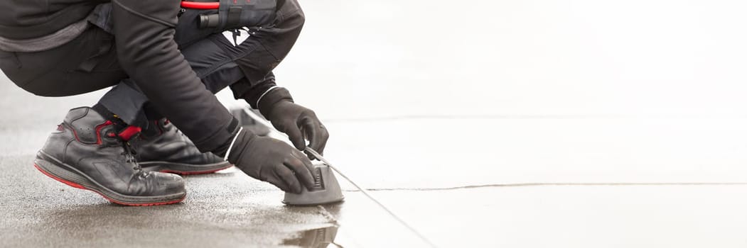 Ground wire. A worker lays a ground cable on the roof of a building. Electrician fixing aluminum wire for grounding solar panels.