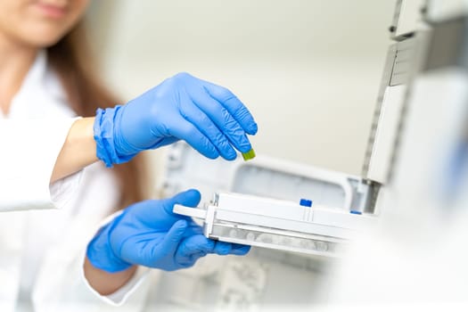conducting chemical experiments in modern devices in a research laboratory. inserting the container with the solution into the measuring device.