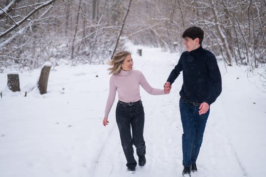 A young couple walks in the park in winter without jackets