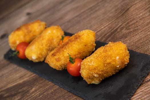 Homemade traditional Spanish croquettes or croquetas on a black plate with fork, Tapas food, High quality photo