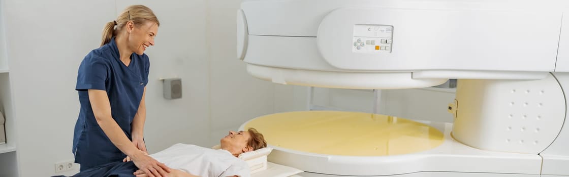 Radiologist controls MRI or CT Scan with patient undergoing procedure. High Tech medical equipment