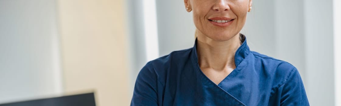 Close up of doctor in uniform standing with crossing hands in clinic. High quality photo