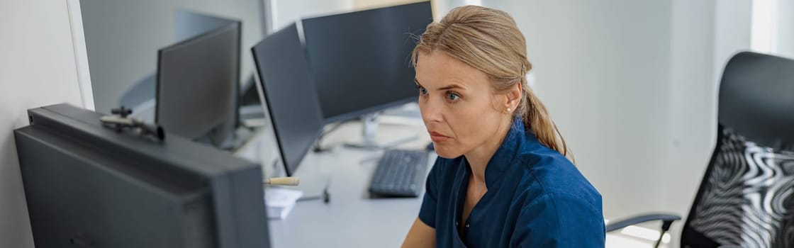 Nurse on Duty working on computer at the Reception Desk in modern clinic. High quality photo