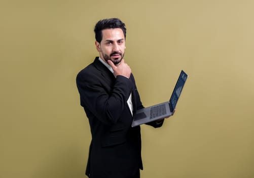 Successful businessman in black suit with innovative tech concept, standing pose and holding laptop and smiling with excitement on copyspace background for promotion or advertisement. Fervent
