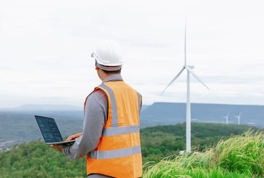 Engineer working on a wind farm atop a hill or mountain in the rural. Progressive ideal for the future production of renewable, sustainable energy. Energy generation from wind turbine.