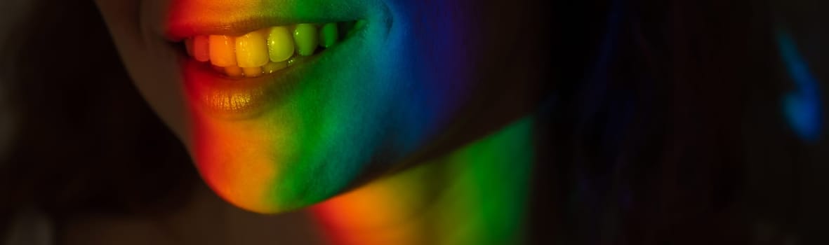 Close-up portrait of smiling woman with ray of rainbow light on her face