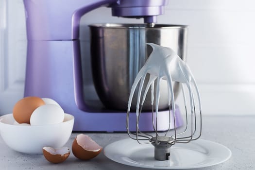 Modern mixer on the kitchen table with eggs and whipped meringue.