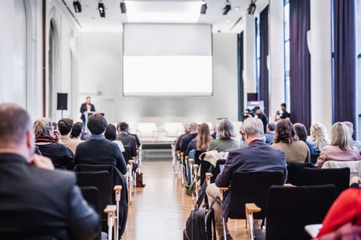 Speaker giving a talk in conference hall at business event. Rear view of unrecognizable people in audience at the conference hall. Business and entrepreneurship concept