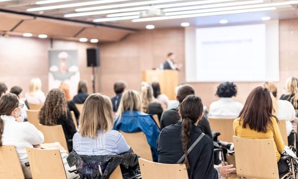 Speaker giving a talk in conference hall at business event. Rear view of unrecognizable people in audience at the conference hall. Business and entrepreneurship concept