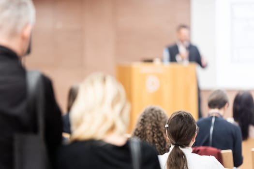 Speaker giving a talk in conference hall at business event. Rear view of unrecognizable people in audience at the conference hall. Business and entrepreneurship concept