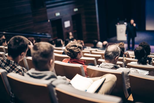 Speaker giving a talk in conference hall at business event. Rear view of unrecognizable people in audience at the conference hall. Business and entrepreneurship concept