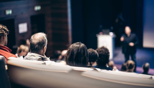 Speaker giving a talk in conference hall at business event. Rear view of unrecognizable people in audience at the conference hall. Business and entrepreneurship concept