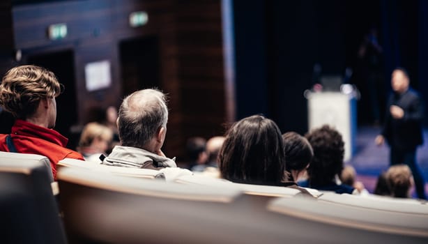 Speaker giving a talk in conference hall at business event. Rear view of unrecognizable people in audience at the conference hall. Business and entrepreneurship concept