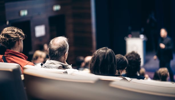 Speaker giving a talk in conference hall at business event. Rear view of unrecognizable people in audience at the conference hall. Business and entrepreneurship concept