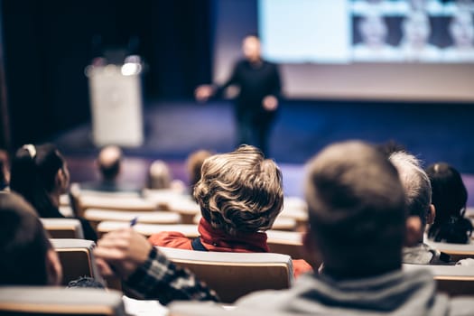 Speaker giving a talk in conference hall at business event. Rear view of unrecognizable people in audience at the conference hall. Business and entrepreneurship concept