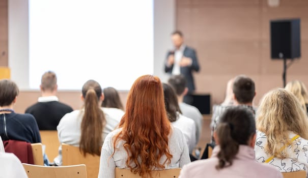 Speaker giving a talk in conference hall at business event. Rear view of unrecognizable people in audience at the conference hall. Business and entrepreneurship concept