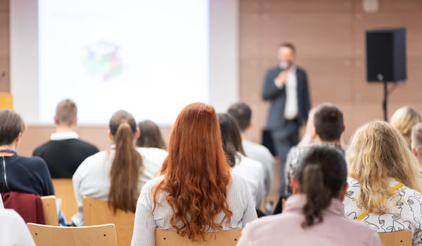 Speaker giving a talk in conference hall at business event. Rear view of unrecognizable people in audience at the conference hall. Business and entrepreneurship concept