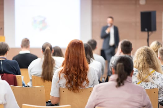 Speaker giving a talk in conference hall at business event. Rear view of unrecognizable people in audience at the conference hall. Business and entrepreneurship concept