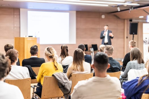 Speaker giving a talk in conference hall at business event. Rear view of unrecognizable people in audience at the conference hall. Business and entrepreneurship concept