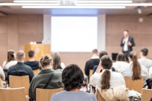 Speaker giving a talk in conference hall at business event. Rear view of unrecognizable people in audience at the conference hall. Business and entrepreneurship concept