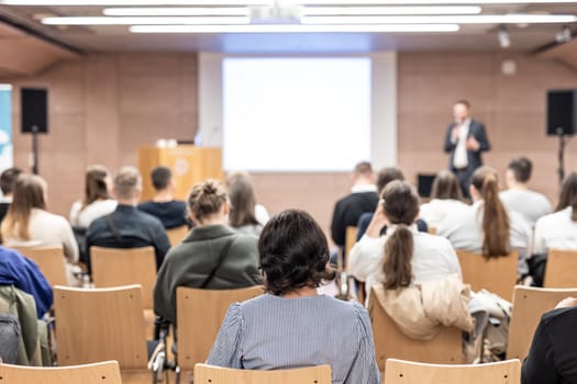 Speaker giving a talk in conference hall at business event. Rear view of unrecognizable people in audience at the conference hall. Business and entrepreneurship concept