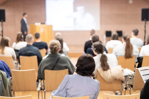 Speaker giving a talk in conference hall at business event. Rear view of unrecognizable people in audience at the conference hall. Business and entrepreneurship concept