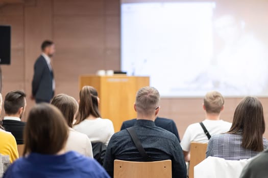 Speaker giving a talk in conference hall at business event. Rear view of unrecognizable people in audience at the conference hall. Business and entrepreneurship concept