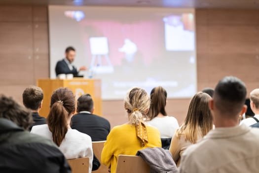 Speaker giving a talk in conference hall at business event. Rear view of unrecognizable people in audience at the conference hall. Business and entrepreneurship concept