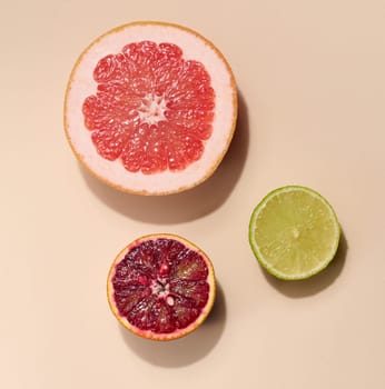 Sliced pieces of orange, lime and grapefruit on a beige background, top view