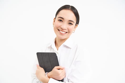 Portrait of businesswoman working on digital tablet, creating diagrams for meeting conference on gadget, standing over white background.