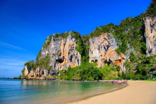 Long tail boats along cliff rocks near the beach, Tonsai Bay, Railay Beach, Ao Nang, Krabi, Thailand.