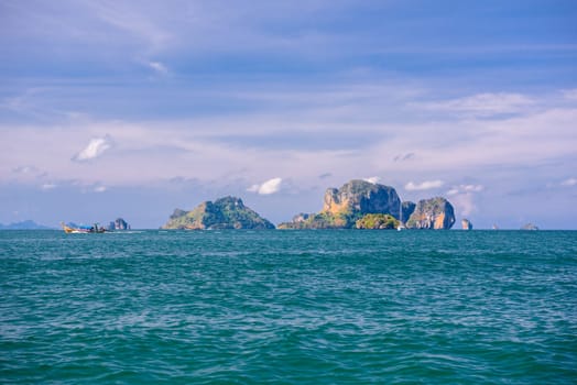 Men in long tail boats with Ko Poda and Ko Kai Chicken Island in the background, Tonsai Bay, Railay Beach, Ao Nang, Krabi, Thailand.