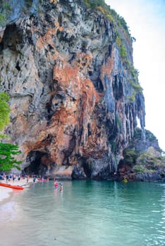 People standing in the water in Princess cave near cliff rock (Phra Nang Shrine Temple), Ao Phra Nang Beach, Ao Nang, Krabi, Thailand.