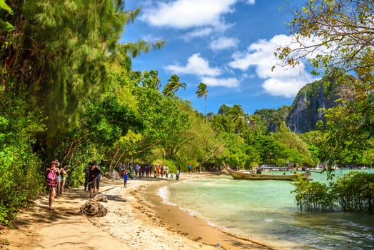Tourists people, long boats, tropical trees and azure water on Ao Phra Nang Beach, Railay east Ao Nang, Krabi, Thailand.