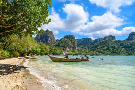 Long boats, rocks and cliffs covered with tropical trees, azure water on Ao Phra Nang Beach, Railay east Ao Nang, Krabi, Thailand.
