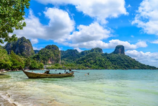 Long boats, rocks and cliffs covered with tropical trees, azure water on Ao Phra Nang Beach, Railay east Ao Nang, Krabi, Thailand.
