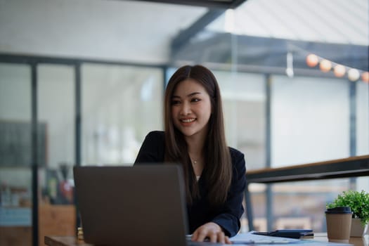 Portrait of a woman business owner showing a happy smiling face as he has successfully invested her business using computers and financial budget documents at work.