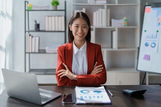 Portrait of a woman business owner showing a happy smiling face as he has successfully invested her business using computers and financial budget documents at work.