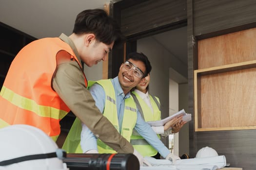 multi ethnic engineer brainstorming and measuring for cost estimating on blueprint and floor plan drawings about design architectural and engineering for houses and buildings.