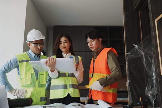 multi ethnic engineer brainstorming and measuring for cost estimating on paperworks and floor plan drawings about design architectural and engineering for houses and buildings.