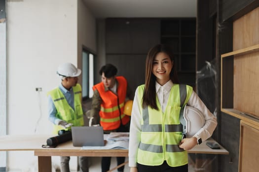 woman smile with multi ethnic engineer brainstorming and measuring for cost estimating on blueprint and floor plan drawings about design architectural and engineering for houses and buildings.