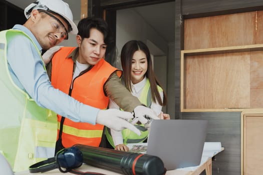 multi ethnic engineer brainstorming and measuring for cost estimating on blueprint and floor plan drawings about design architectural and engineering for houses and buildings.