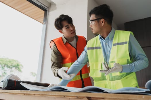 multi ethnic engineer brainstorming and measuring for cost estimating on blueprint and floor plan drawings about design architectural and engineering for houses and buildings.